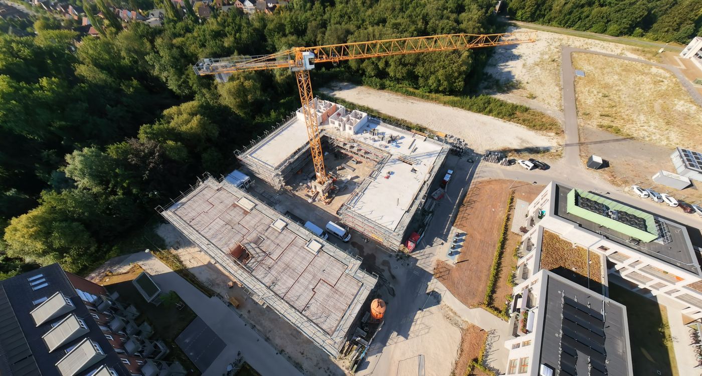Luftbild der Baustelle: zwei Gebäude im Rohbau mit Turmdrehkran